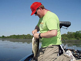 Unhooking a nice largemouth bass caught on a 6 inch ribbon tail Berkley Power Worm from Lake Ovid.