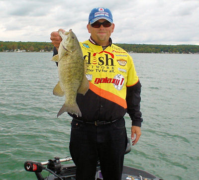 Pro angler Mickey Thomas poses with a 4.5 pound smallmouth bass caught from Burt & Mullett Lakes in Northern Michigan. Thomas participates in 